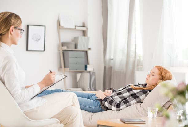 The power of hypnotherapy A client lying on a sofa while a therapist takes notes