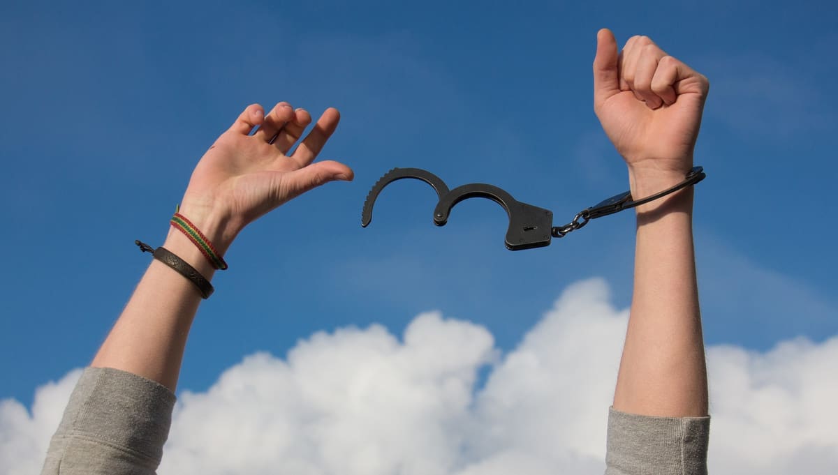 Hypnotherapy for addiction Hands breaking free from handcuffs against a blue sky