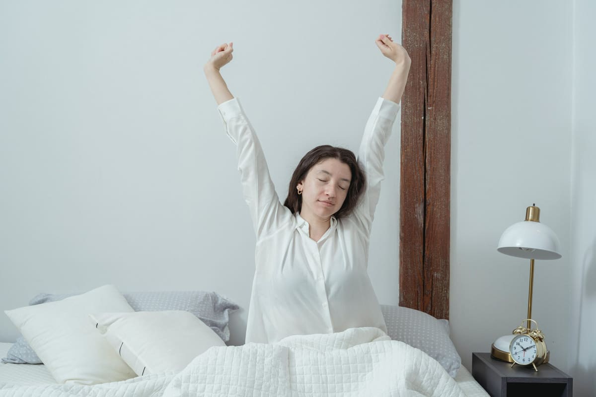 Hypnotherapy for sleep and insomnia A woman stretching in bed as she wakes up refreshed